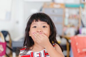Young girl covering her mouth with her hand