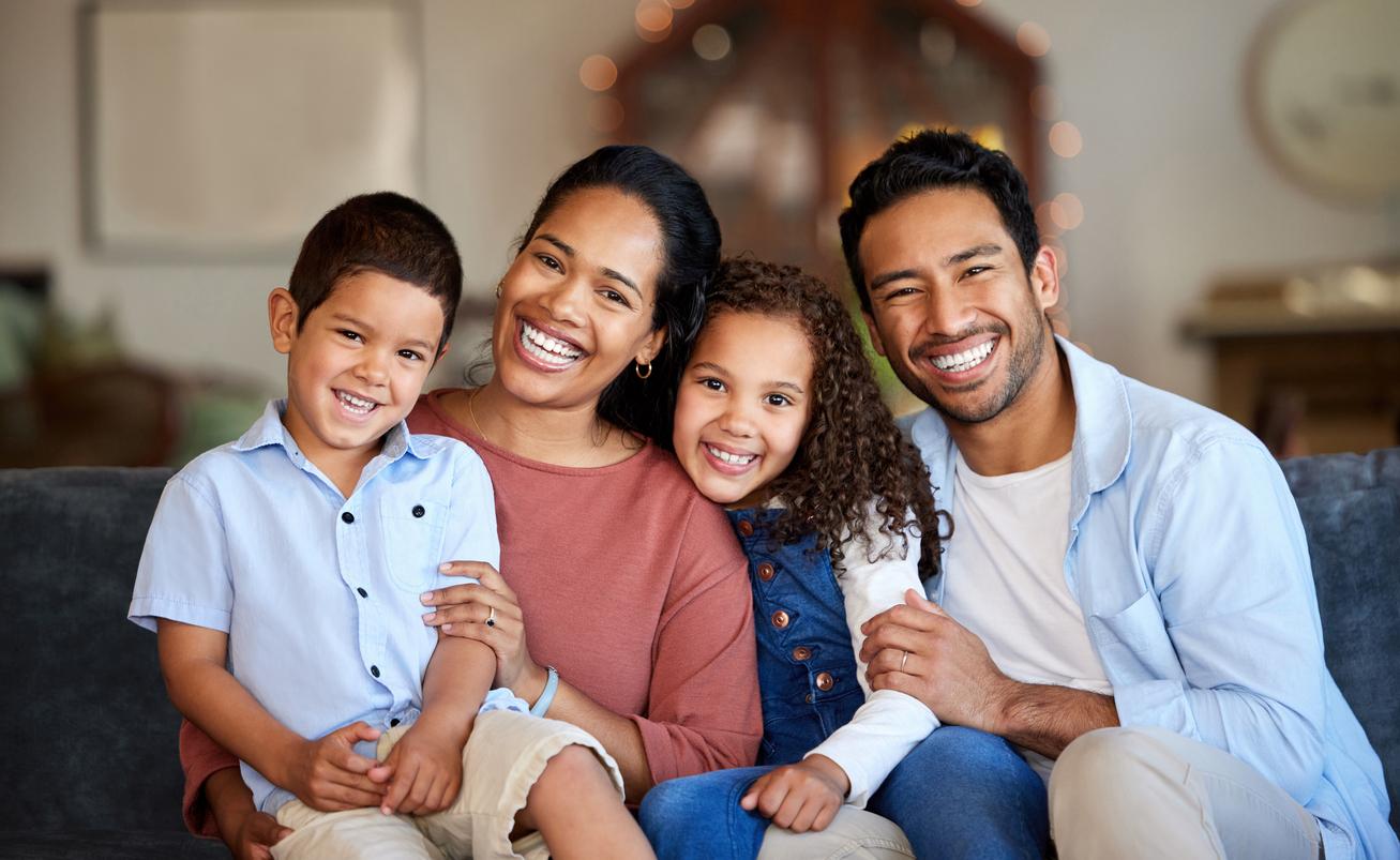 A smiling family of four with incredibly white teeth.