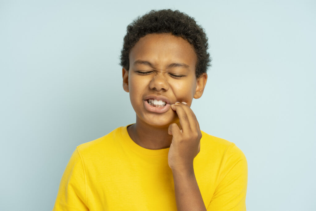 A child holds their cheek in pain.